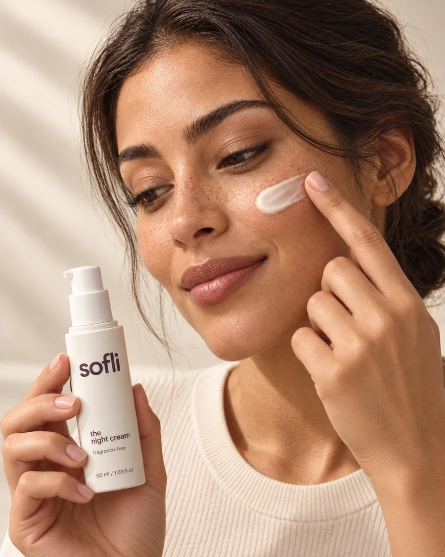 A woman gently applying a small swipe of cream to her cheek